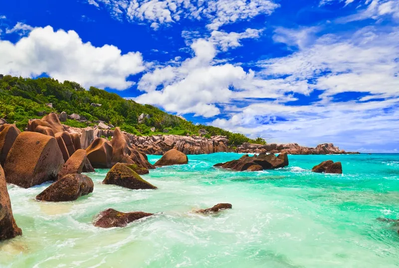 Tropischer Strand auf den Seychellen mit charakteristischen Granitfelsen und türkisblauem Wasser.